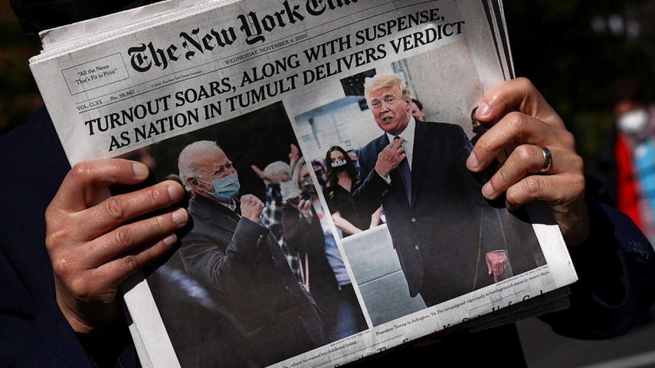 A man holds a newspaper on Black lives Matter plaza near the White House after Election Day in Washington, U.S., November 4, 2020. REUTERS/Hannah McKay     TPX IMAGES OF THE DAY