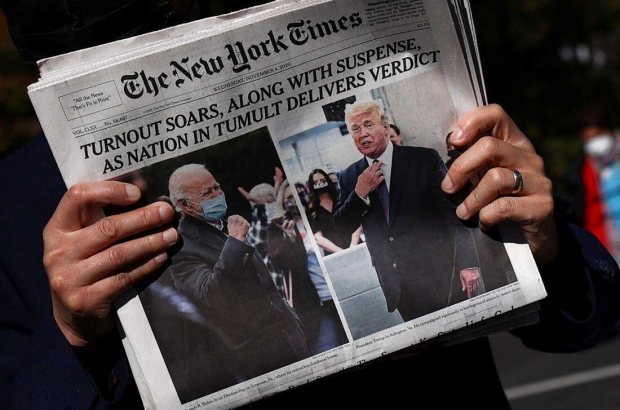 A man holds a newspaper on Black lives Matter plaza near the White House after Election Day in Washington, U.S., November 4, 2020. REUTERS/Hannah McKay     TPX IMAGES OF THE DAY